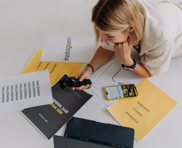 Magda Lelicka przy aparacie, telefonie i materiałach dotyczących strategii oraz marketingu Agencji LIMON