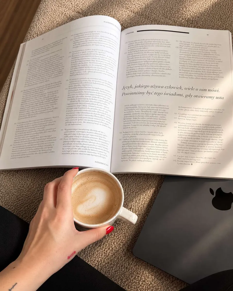 Kawa i otwarty papierowy magazyn obok laptopa — chwila czytania poza światem algorytmów